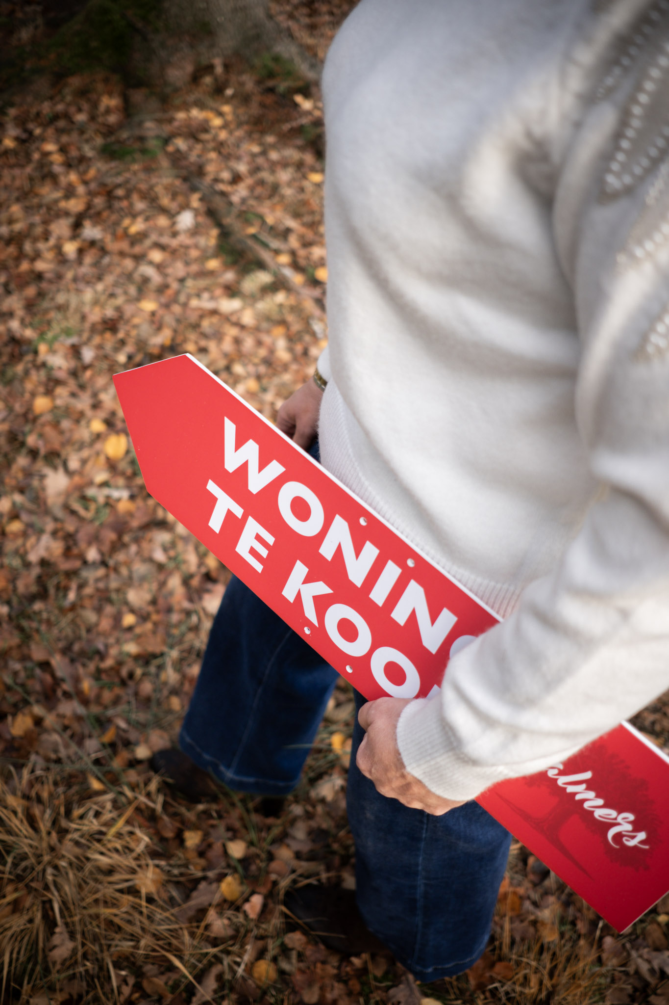 Vrouw met een plakaat waarop 'woning te koop' staat